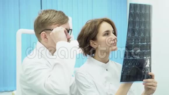 两位医生正在看x光媒体男性和女性主任医师在明亮的光线下观察x射线MRI视频的预览图