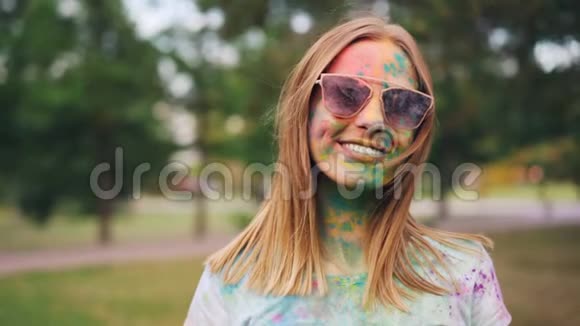 快乐女孩的慢镜头肖像脏脸和T恤站在霍利节看着相机微笑着视频的预览图
