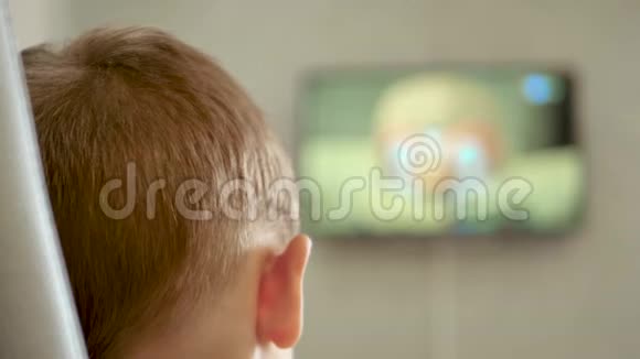 一个孩子正坐在椅子上看一幅漫画电视屏幕失去了焦点视频的预览图
