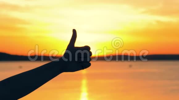 手轴剪影特写金色夕阳下太阳升起时拇指向上的姿态视频的预览图