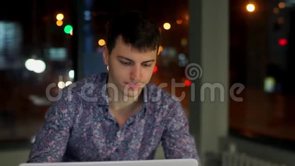 一个男经理在笔记本电脑里工作生气在窗外的背景下夜城视频的预览图
