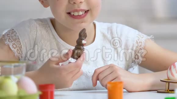 快乐的小女孩享受美味的巧克力兔子甜蜜的复活节礼物童年视频的预览图