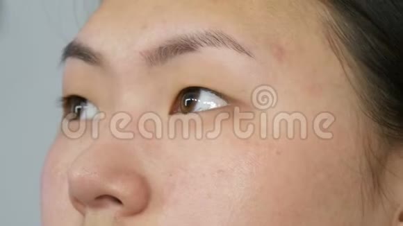 一位专业的化妆师将带有特殊画笔的遮瑕膏应用于视觉工作室特写的亚洲女孩模特脸上视频的预览图