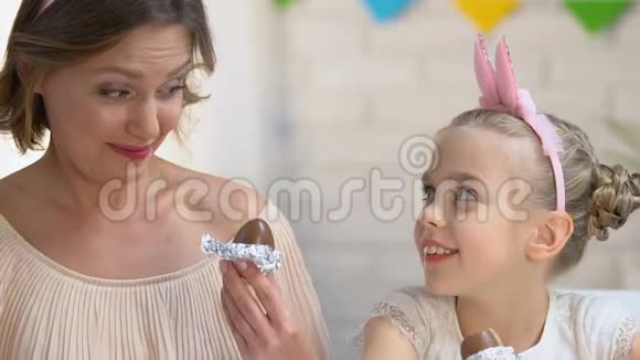 可爱的女儿和母亲一起吃巧克力蛋享受消遣家人视频的预览图
