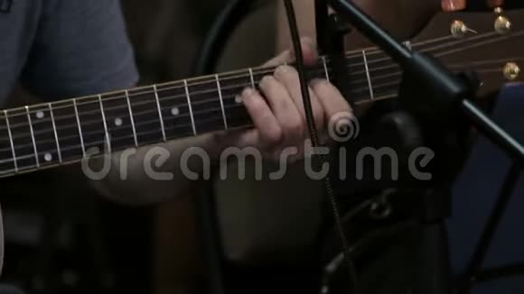 男性手夹住声吉他上的弦以进行声音提取独奏音乐家或节奏吉他手特写视频的预览图