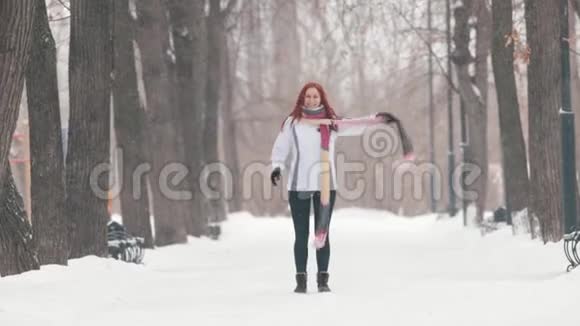 冬季公园一个留着鲜红头发的女人站在人行道上做活动视频的预览图