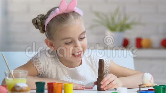 可爱的女孩在玩巧克力兔子在镜头里微笑童年视频的预览图
