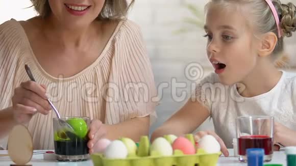 小孩子兴奋地看着妈妈穿着绿色食物染色的垂死蛋复活节装饰视频的预览图