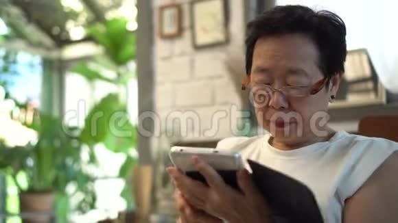 戴眼镜的亚洲老年妇女视力有问题受数字生活方式的影响视频的预览图