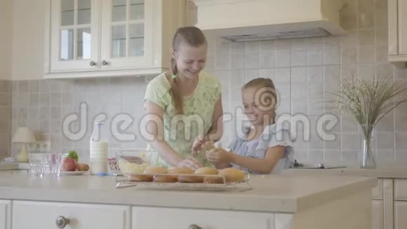 漂亮的年轻妈妈和可爱的小女儿一起在厨房做饭真正幸福的家庭关系妈妈和视频的预览图