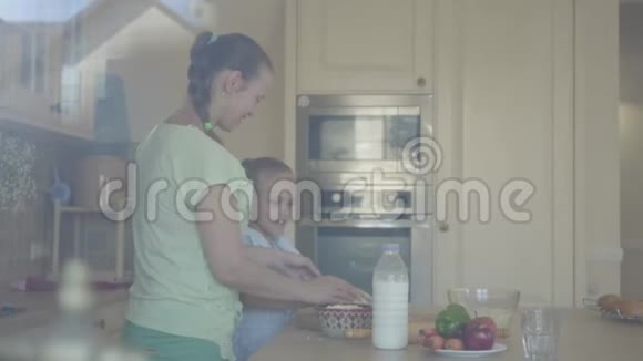 年轻的女人和小女儿在家里厨房里做蛋糕家庭幸福关系妈妈和女儿视频的预览图