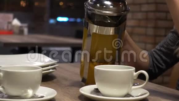 咖啡屋里的女人用杯子从法国媒体上倒出沙棘茶双手特写视频的预览图