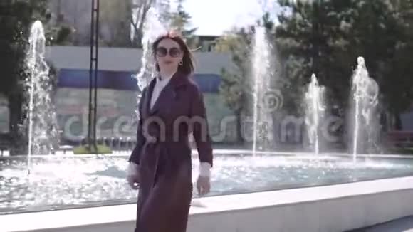 穿着勃艮第夹克礼服的奢华美女走在喷泉附近视频的预览图