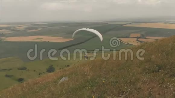 专业滑翔伞降落在山坡上的鸟瞰图滑翔伞运动视频的预览图