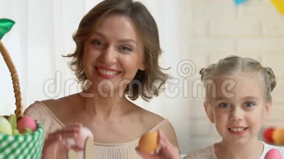 可爱的女儿和妈妈在复活节前夕把彩蛋放进眼睛里玩得很开心视频的预览图