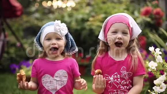 戴着夏天帽子的可爱小女孩在花园里吃着美味的饼干视频的预览图