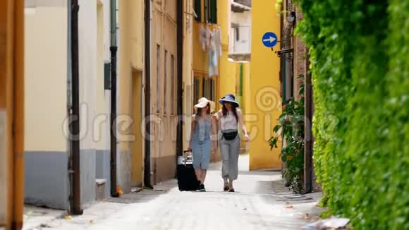 两个穿着睡衣的年轻女人拿着行李箱走在街上视频的预览图