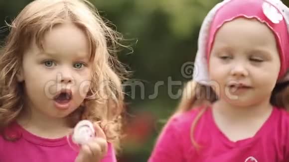 戴着夏天帽子的可爱小女孩在花园里吃着美味的饼干视频的预览图