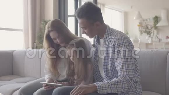 年轻的金发女子白种人和非洲黑人男子坐在一起两人中间是一个可爱的小女儿长着一头浅发视频的预览图