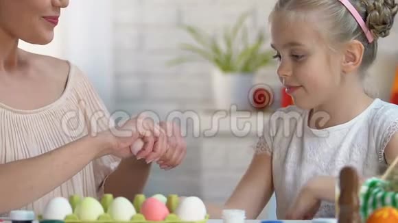 女儿在母亲手中选择粉红色的鸡蛋家人在复活节玩游戏视频的预览图