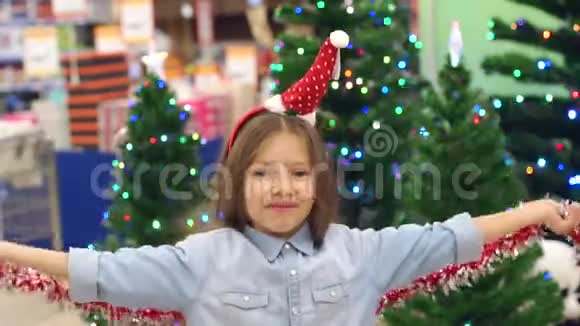 一个戴着圣诞帽的小女孩在超市玩花环视频的预览图