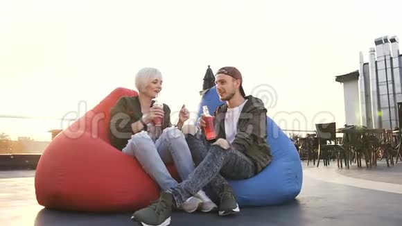 年轻的白种人恋爱中的夫妇坐在咖啡馆里的多色扶手椅上喝着果汁帅呆了视频的预览图