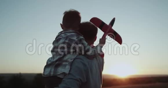 特写镜头拥抱爸爸和儿子抱着一架大飞机看日落视频的预览图