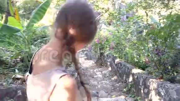 从侧面看女孩在植物之间走下石阶视频的预览图