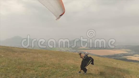 专业滑翔伞的鸟瞰图从山坡上起飞滑翔伞运动视频的预览图