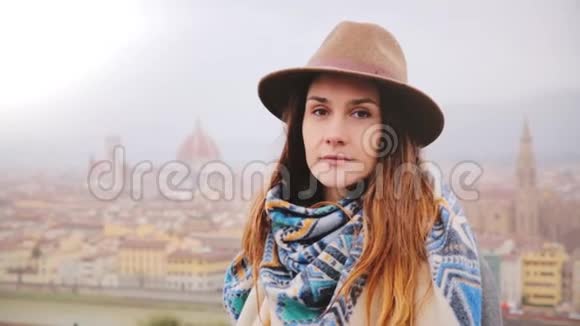 年轻美丽的高加索女孩戴着帽子脸上带着和平神秘的微笑看着雨中的佛罗伦萨的摄像机视频的预览图