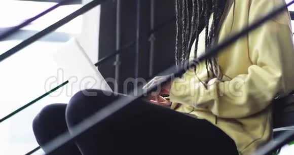 细节特写办公室工作的非洲年轻女士在她的笔记本上工作她坐在楼梯旁视频的预览图