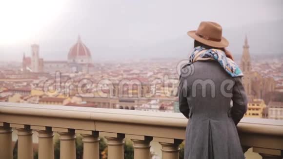 戴帽子的女孩站在观景台欣赏意大利佛罗伦萨的美景在寒冷的阴雨天视频的预览图