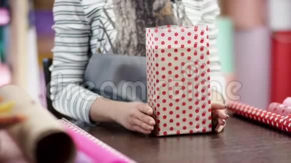 美丽勤劳的女人把蓝色的豪华盒子包装在礼品纸上作为圣诞礼物或生日礼物送给她视频的预览图