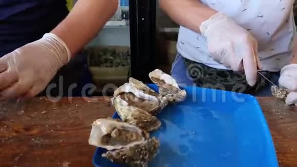 新鲜牡蛎在鱼市开张售货员手里拿着一只牡蛎和一把用来切东西的刀海鲜典型的沿海食品视频的预览图