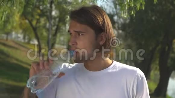 一个年轻人从公园的瓶子里喝水然后开始跑视频的预览图