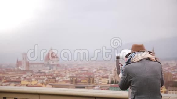 在意大利佛罗伦萨秋天的令人惊叹的城市全景中用硬币操作望远镜返回快乐的年轻女性旅行者视频的预览图
