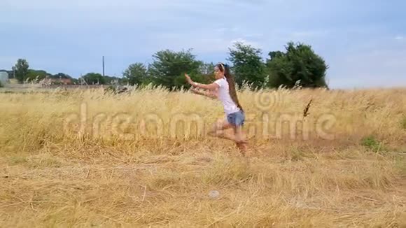 有魅力的苗条女体操运动员长头发穿短裤用金色的草地在球场上进行锻炼视频的预览图
