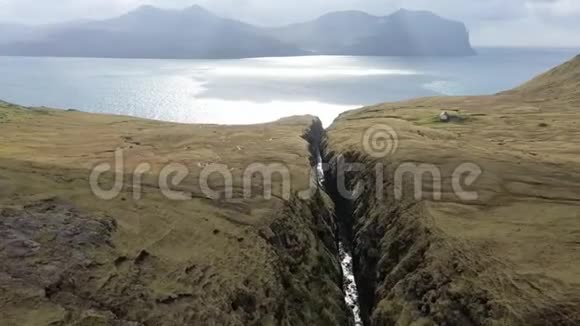 空中沿着狭窄的岩石峡谷飞行通向壮观的法罗群岛广阔的公海呼吸视频的预览图