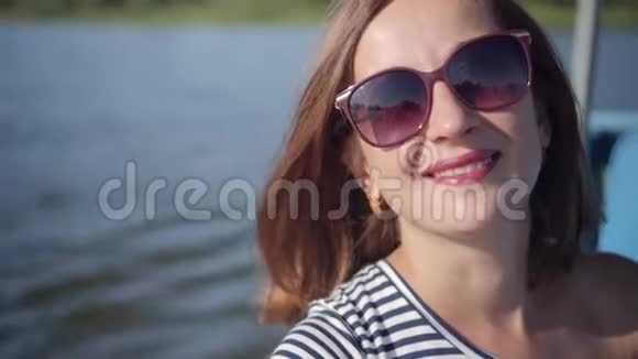 可爱的红发女人戴着太阳镜笑容满面阳光在水中闪烁视频的预览图
