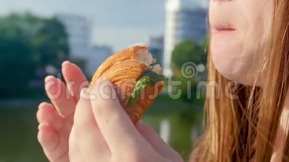 女孩抱着吃美味的牛角面包新鲜的甜点近距离射击视频的预览图