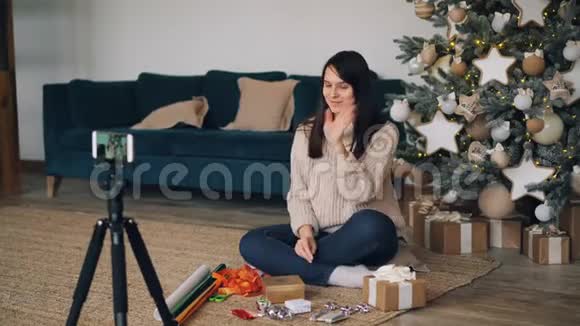 微笑的年轻女士vlogger正在录制关于礼品包装的视频教学订阅者用装饰礼物盒视频的预览图