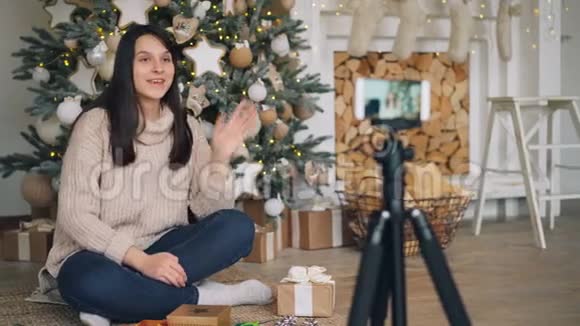 巧妇难为无米之炊的博客作者正在教她的追随者在地上拿着礼物盒装饰圣诞礼物视频的预览图