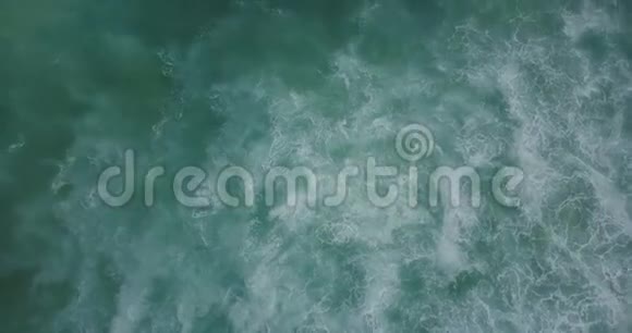 在汹涌的海浪和令人惊叹的蓝色和绿色海泡沫质地之上的无人机上升视频的预览图
