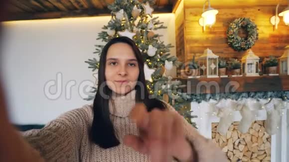 在圣诞节一位心情愉快的女士看着相机交谈展示了一个表达积极的礼物盒视频的预览图