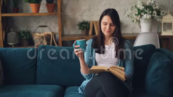 漂亮的女孩正坐在家里的沙发上喝着一杯茶放松地享受着孤独和平静视频的预览图