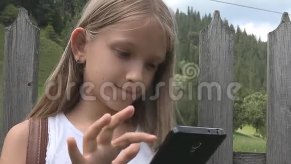 儿童户外玩智能手机儿童浏览平板电脑女孩自然放松视频的预览图