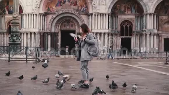 鸽子坐在美丽的女游客的手臂与智能手机附近圣马可大教堂在威尼斯意大利慢动作视频的预览图