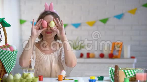 快乐的女人把复活节彩蛋放在眼睛里享受快乐的节日视频的预览图