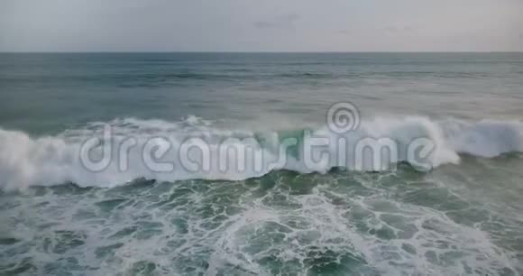 在多云的一天里无人机在巨大的蓝色海浪中向左移动到达海岸并在白色泡沫中坠毁视频的预览图