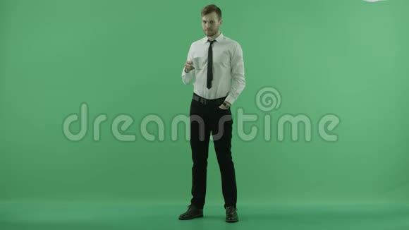 男人从杯子里喝酒在绿色的背景上看时间视频的预览图